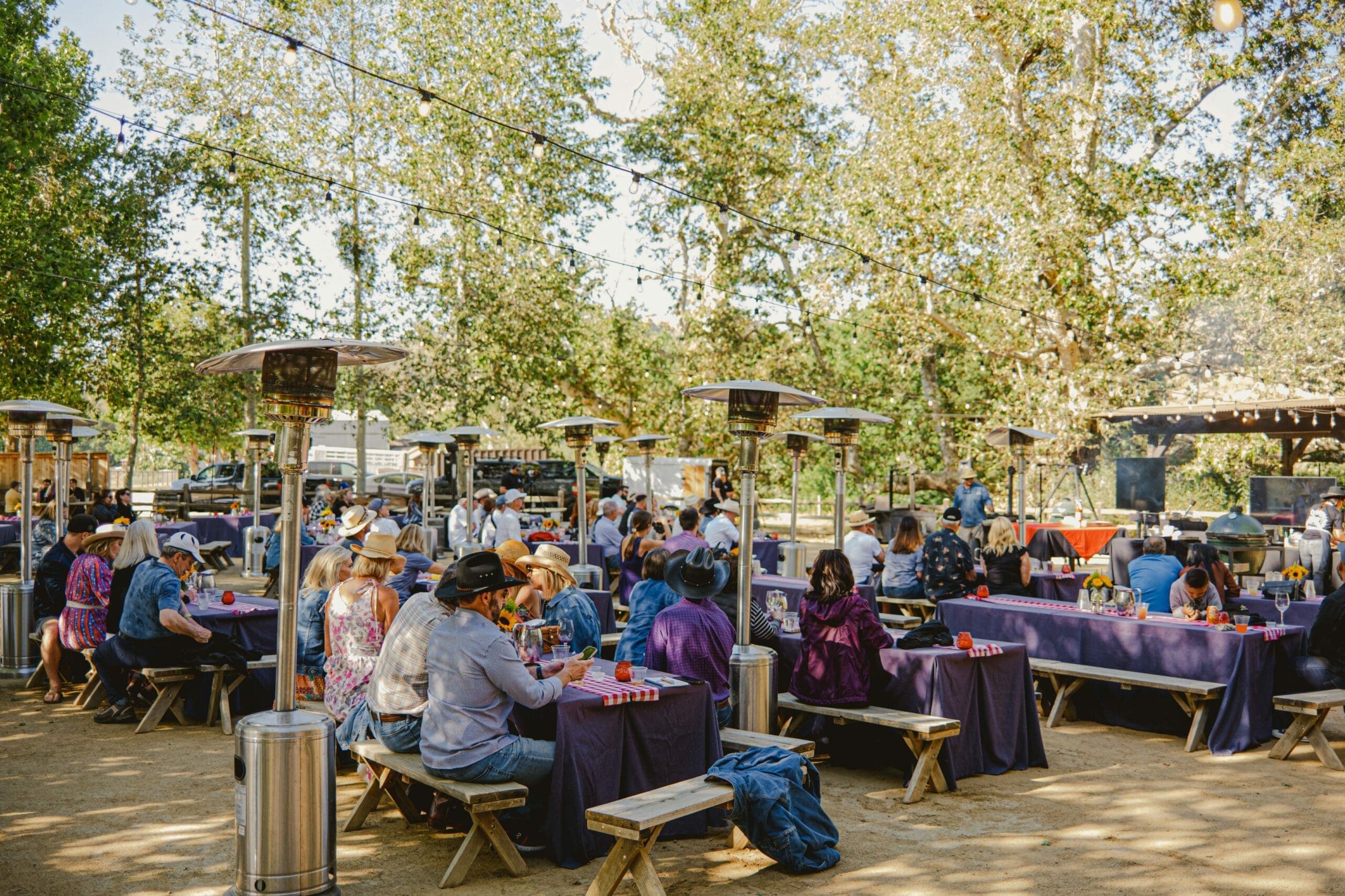 people sitting at tables with heated lamps outdoors