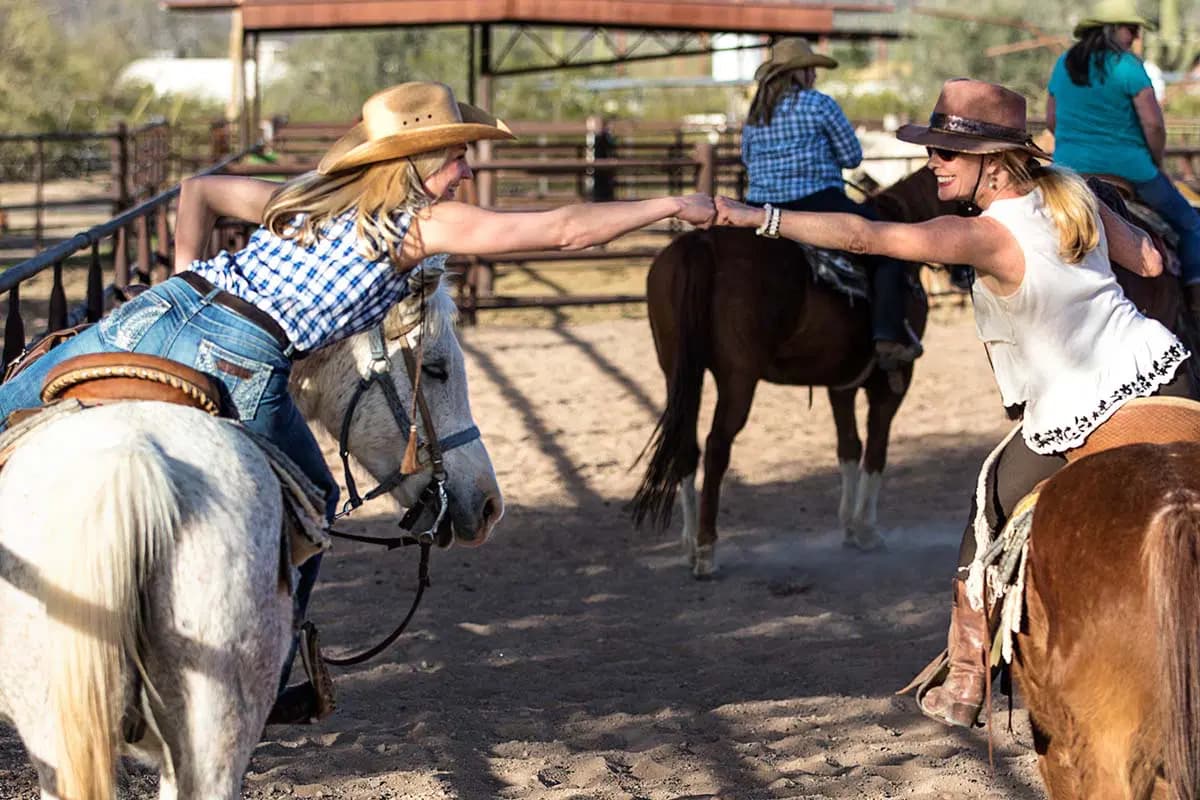 two people fist bumping as they ride their horse