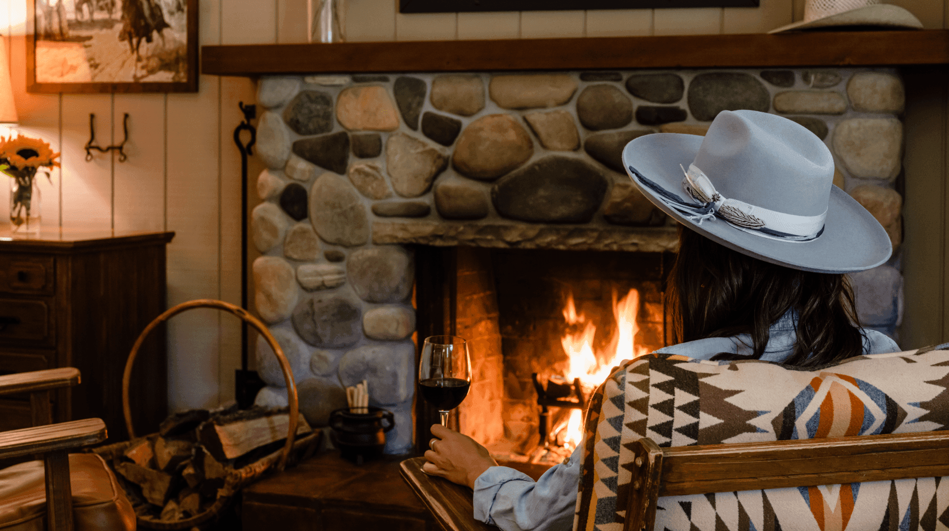 person sitting by fireplace with glass of wine inside Golf View Cottage