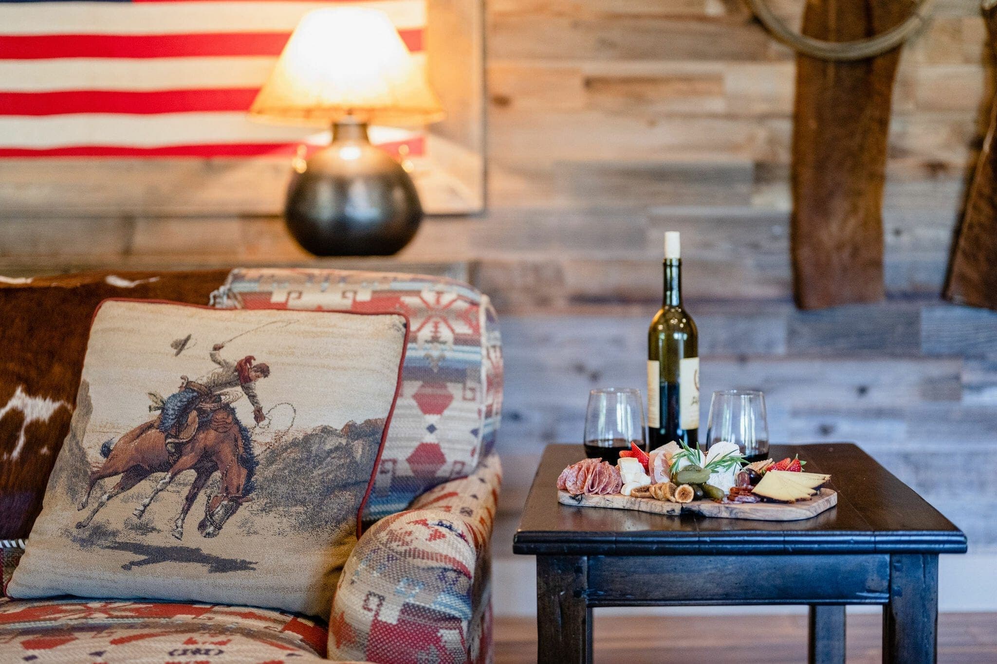 couch and side table with charcuterie board and red wine