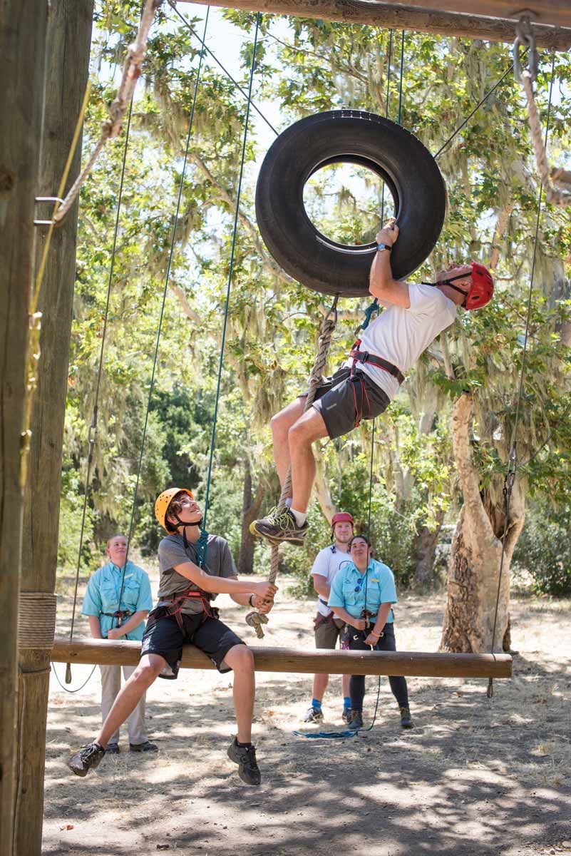 Two adults completing a team building exercise on the ropes course at Alisal Ranch