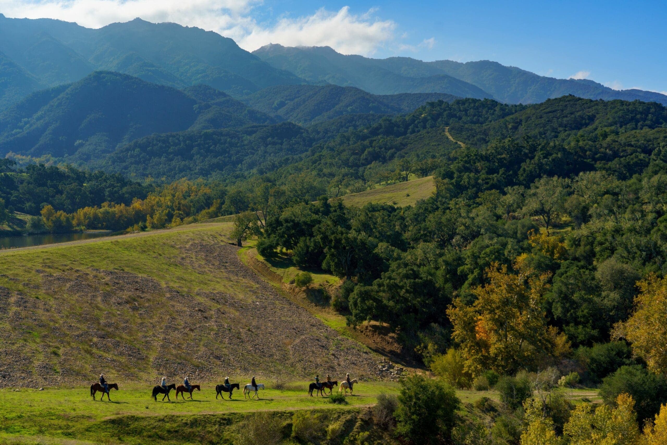 view of the hills as people ride horses on the meadow