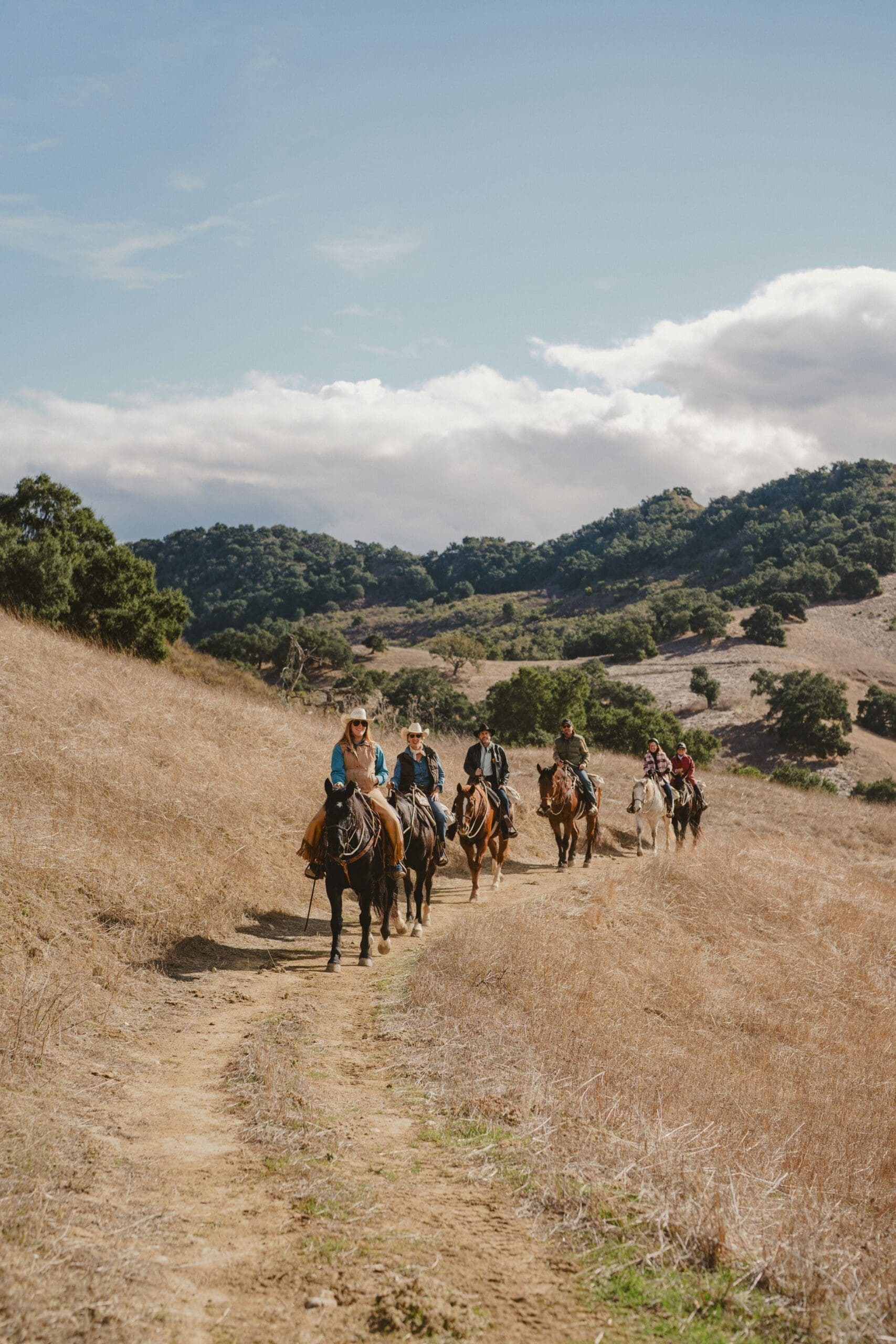 group of people riding horse on a grass field