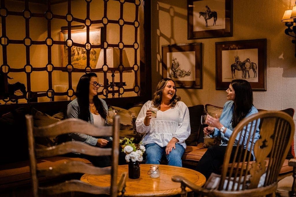 three people drinking at chatting on a couch