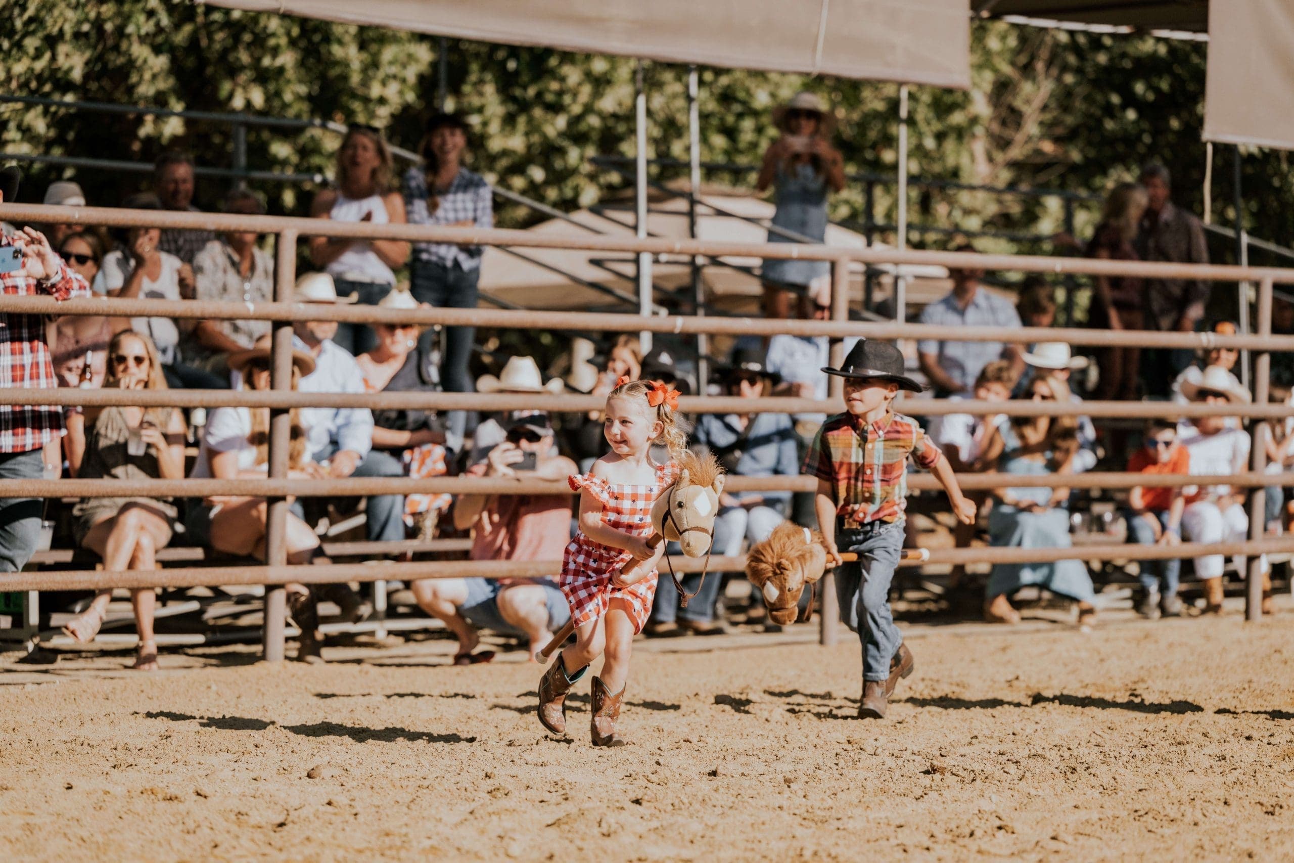 kids running with stick horses inside the Alisal rodeo as people watch