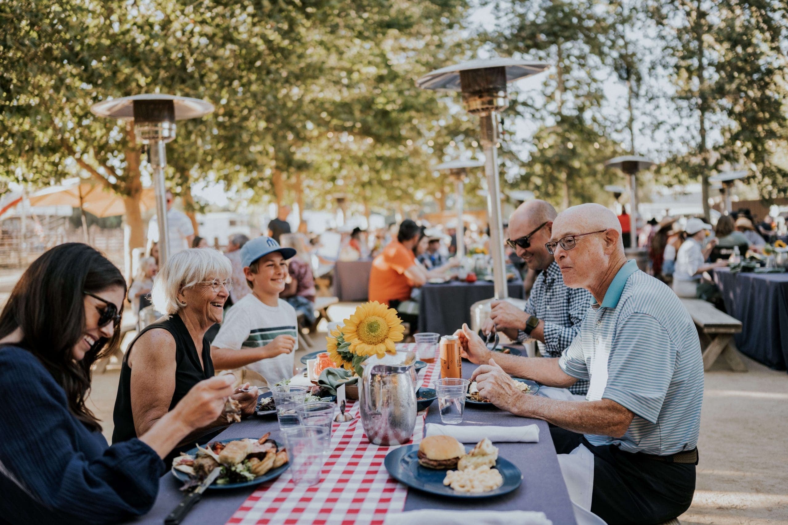 families eating at an outdoor seating area with heated lamps