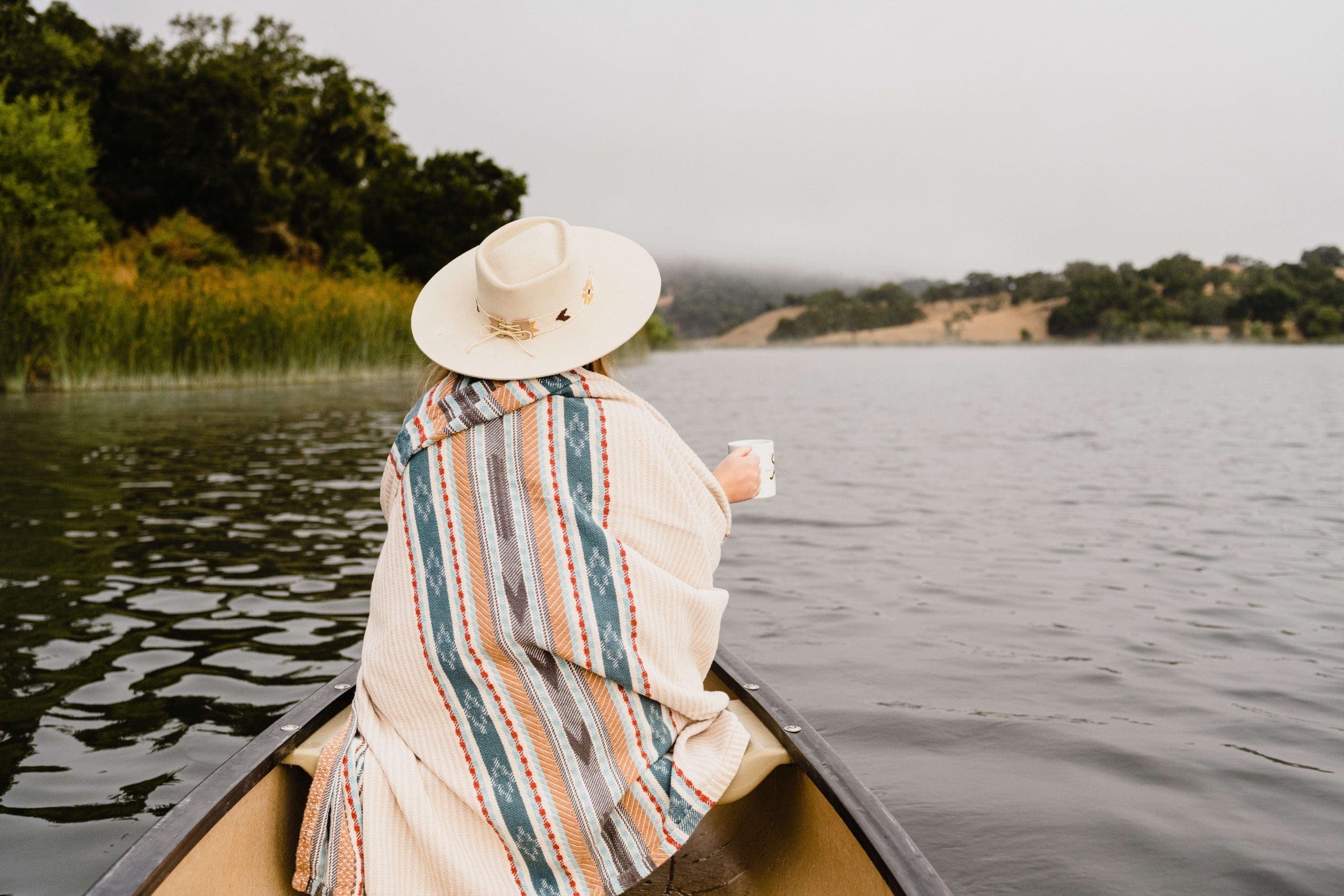 person cozy under a blanket on a canoe