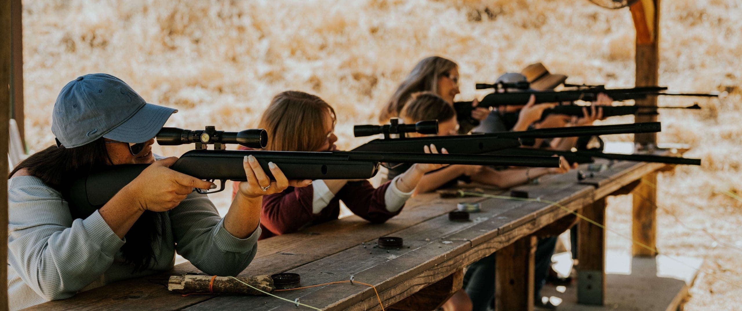 group of people in a row pointing air rifle at targets