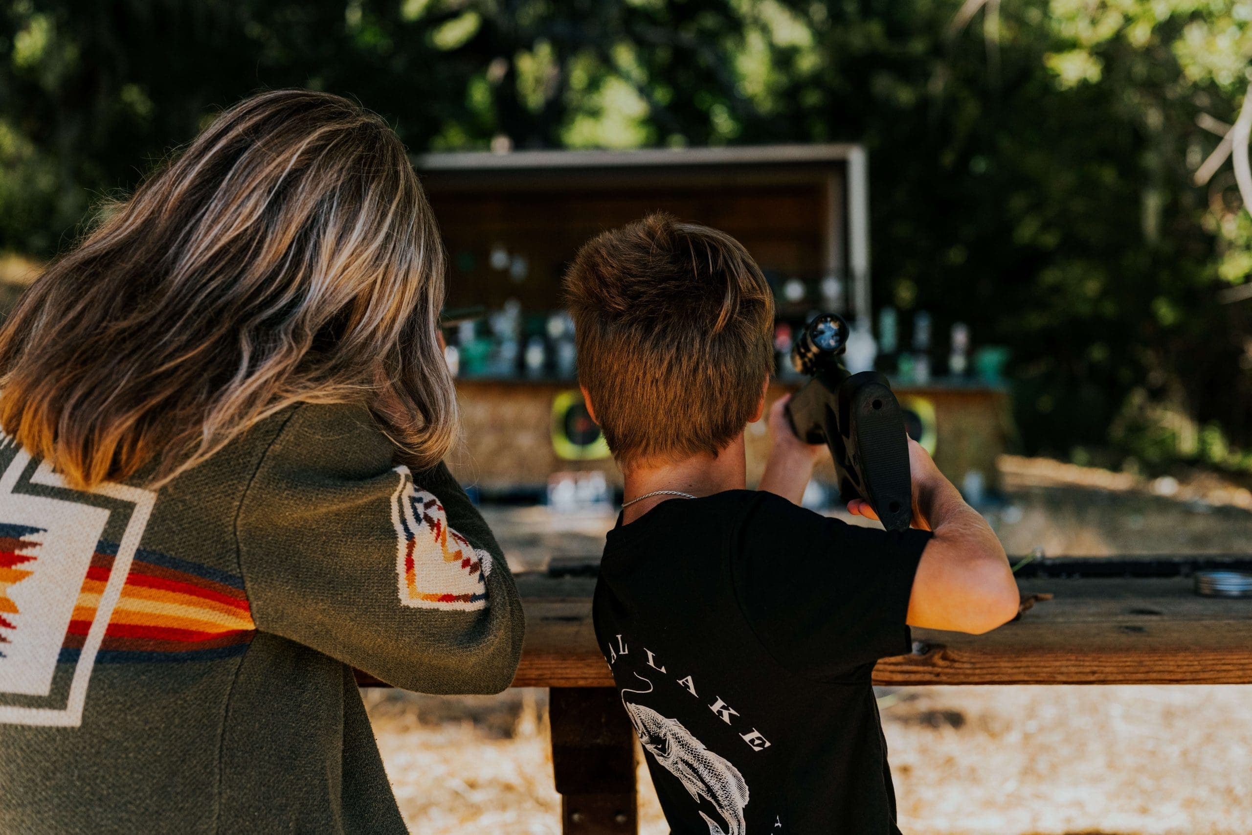 adult and young person pointing air rifles at targets