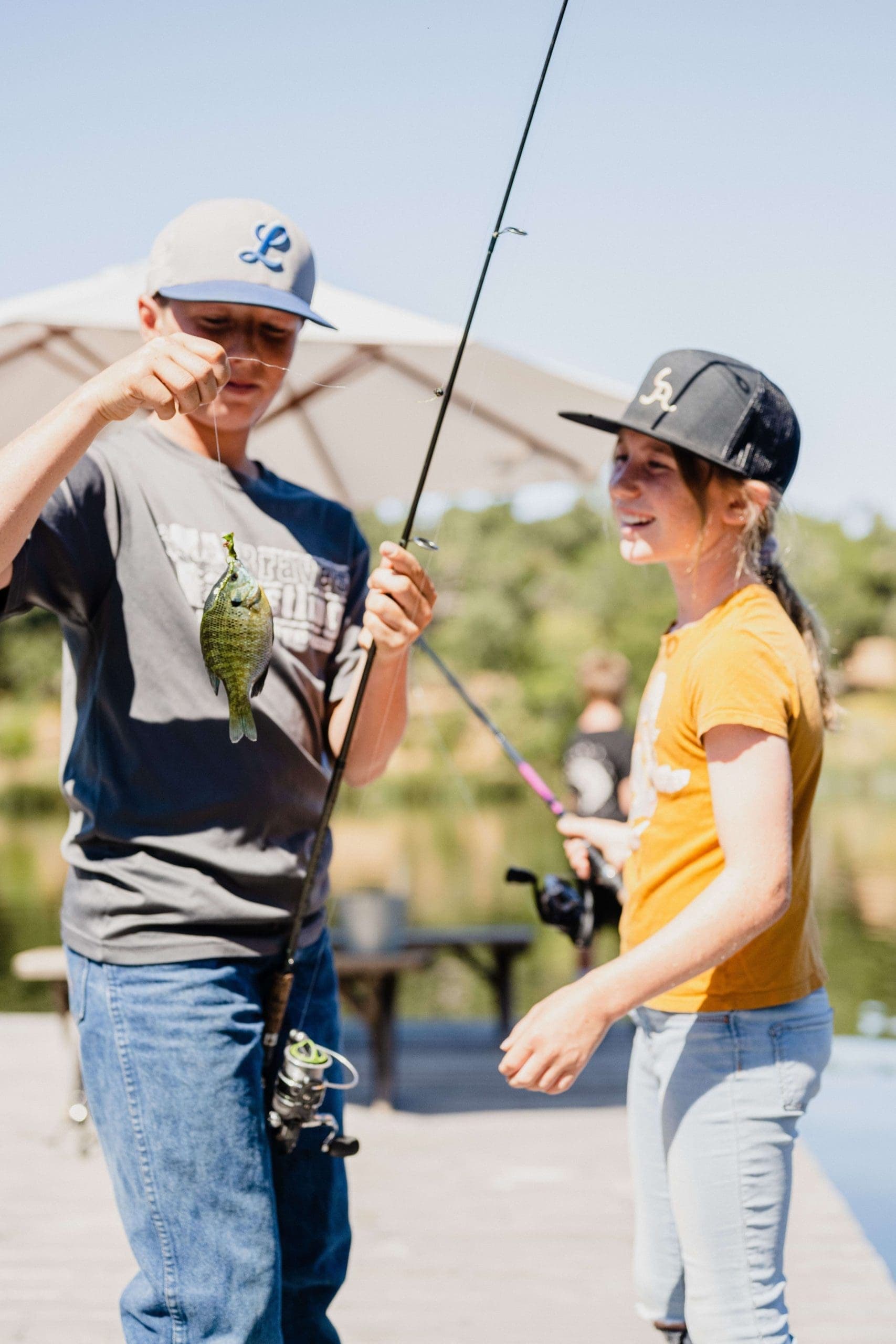 two kids looking at a small fish on hooked to the fishing line