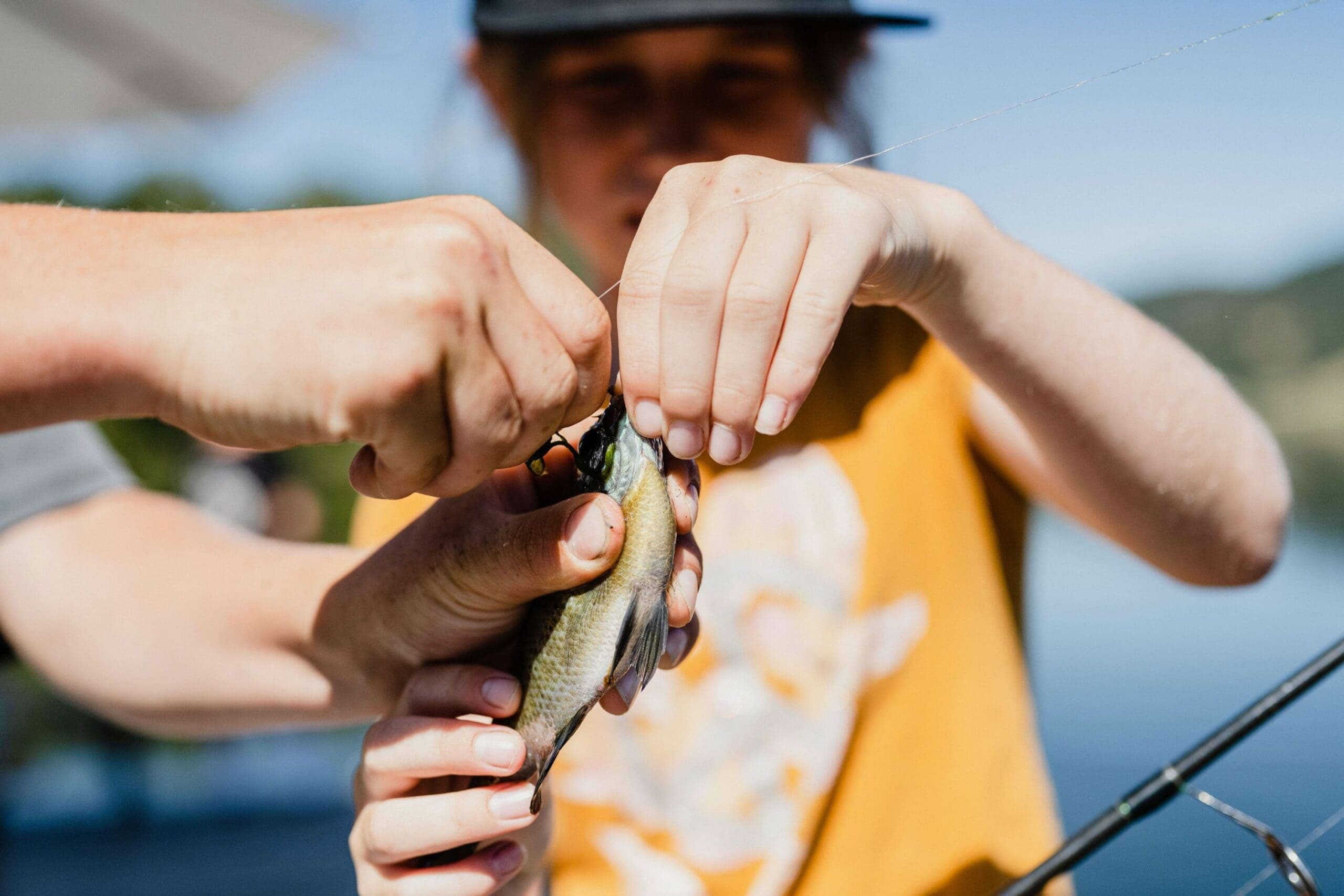 adult helping young person unhook a fish