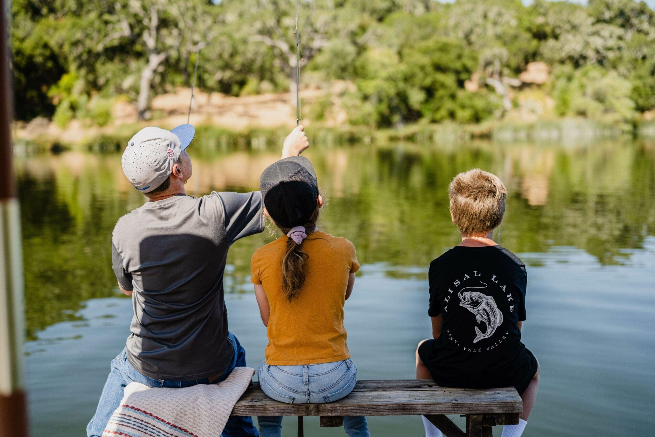 young people fly fishing from a bench