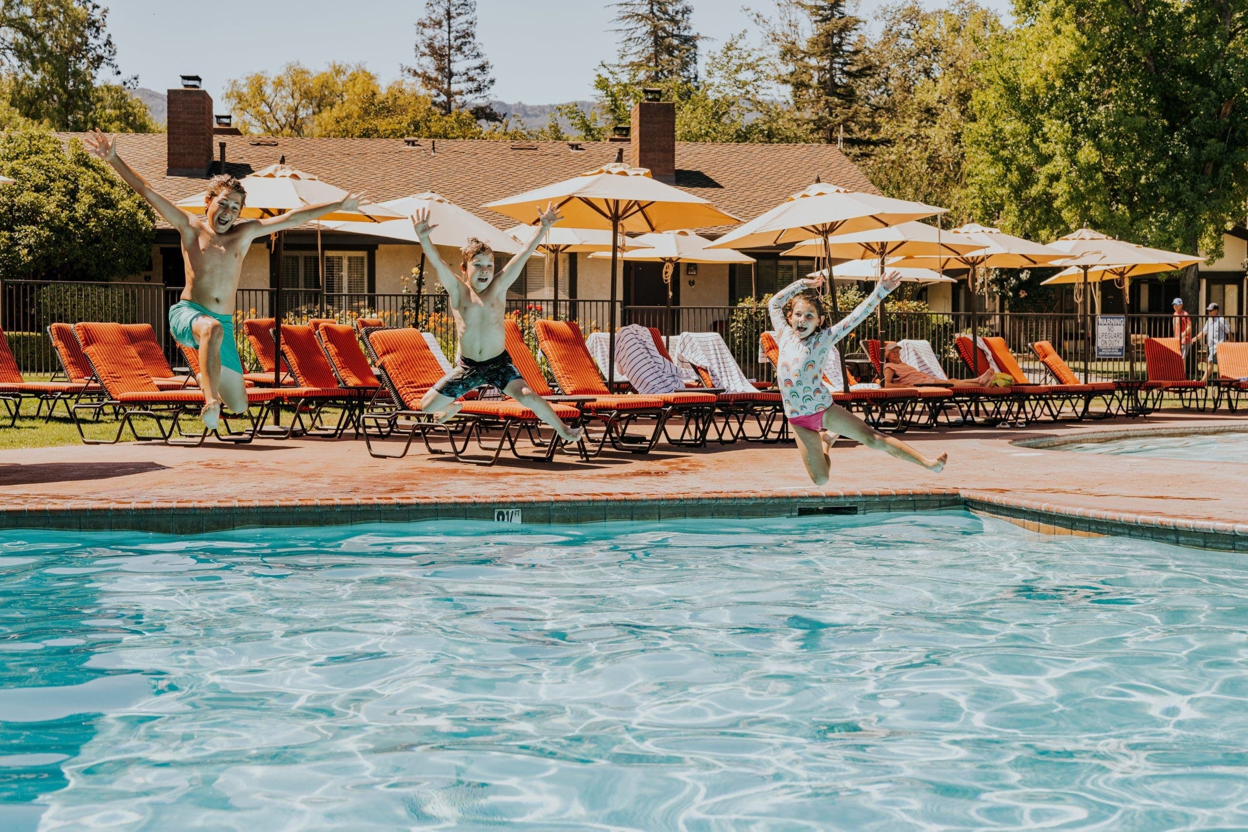 three kids jumping into the outdoor pool