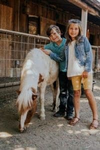 kids standing beside pony