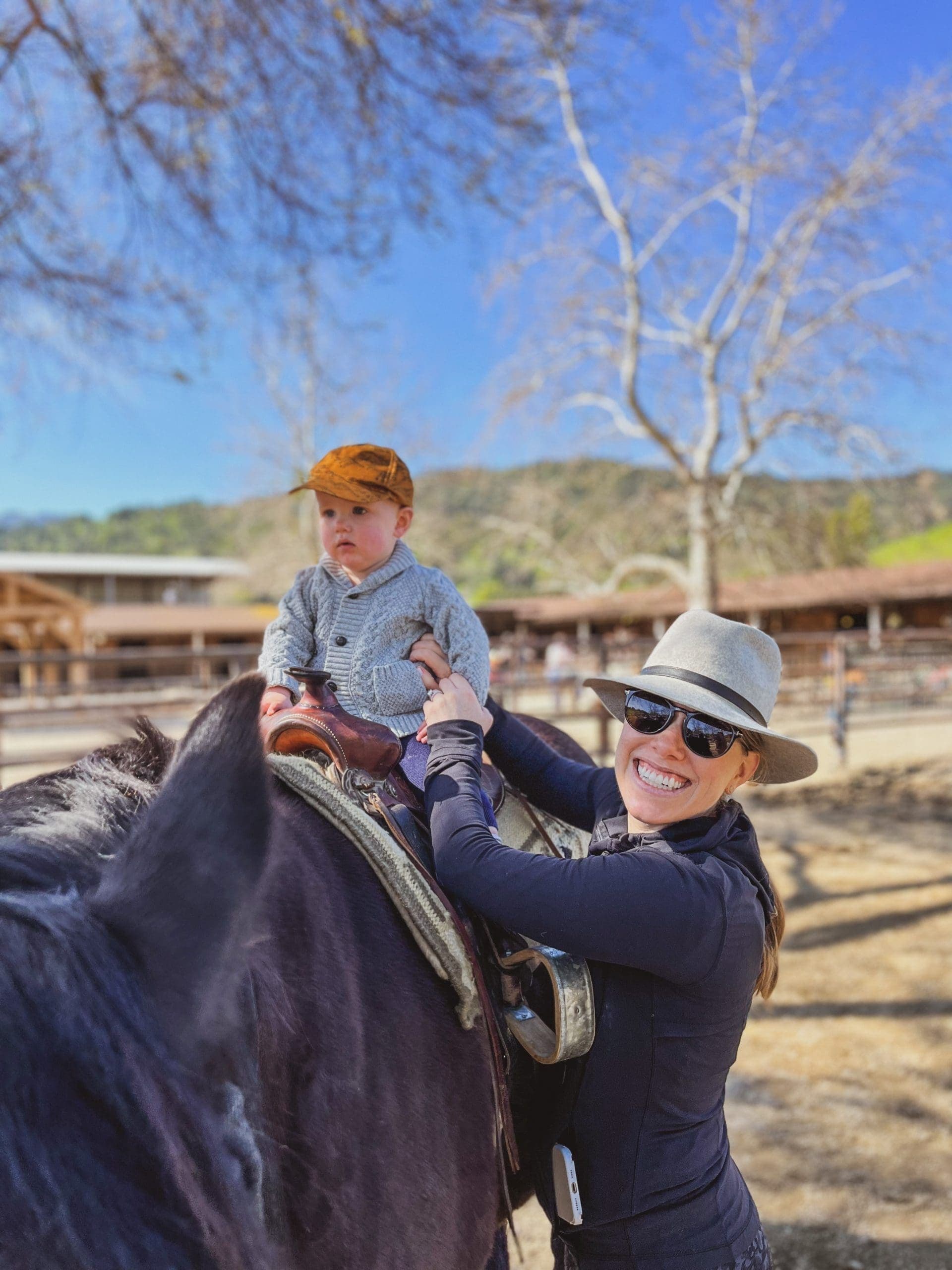 person holding child up to sit on a horse