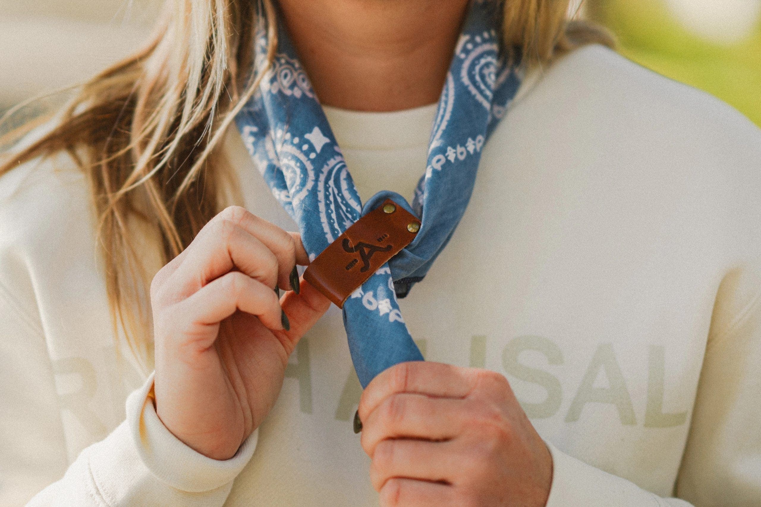 person wearing scarf on neck holding alisal leather clip