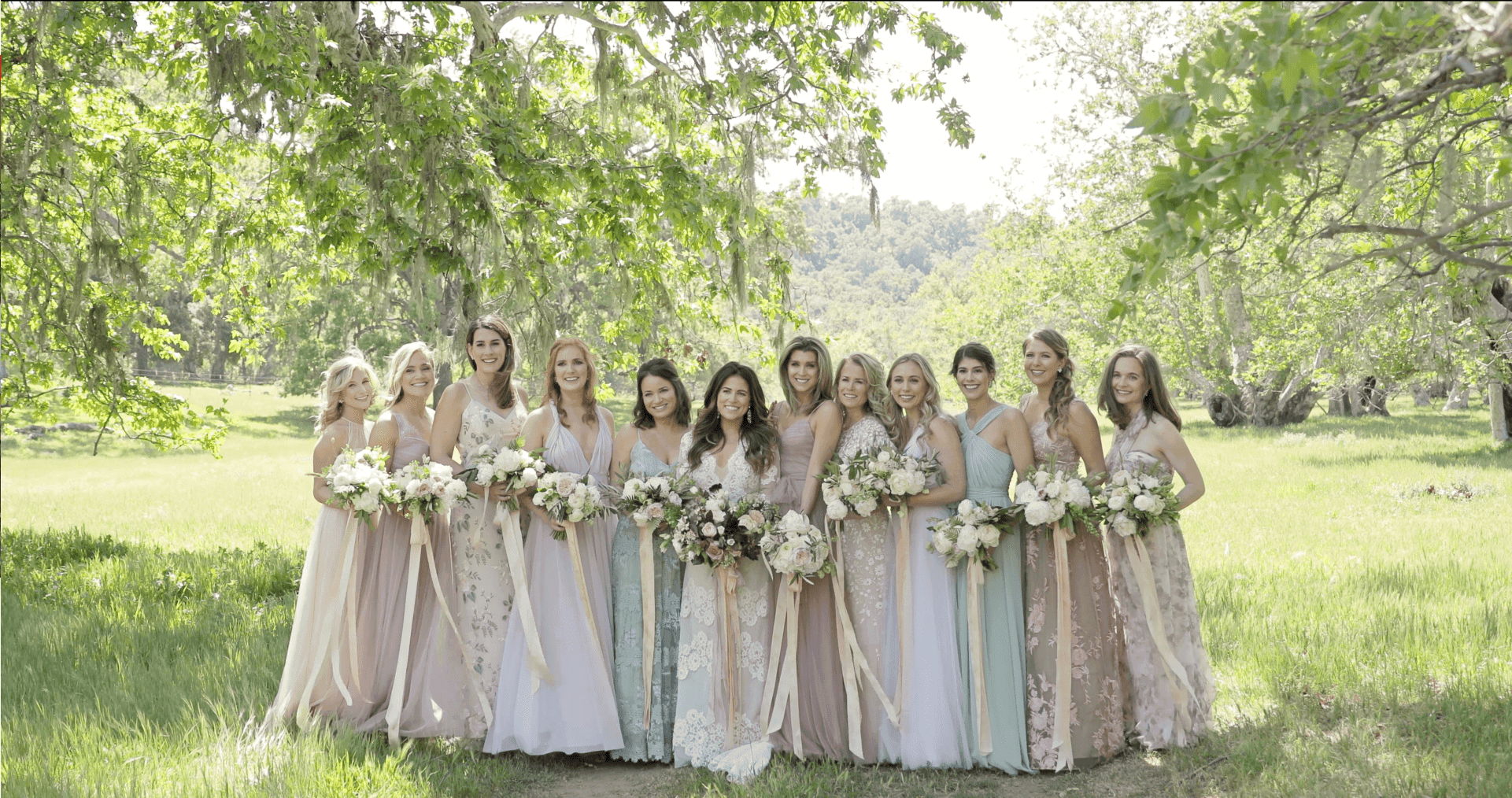 bride and brides maids posing outside under trees