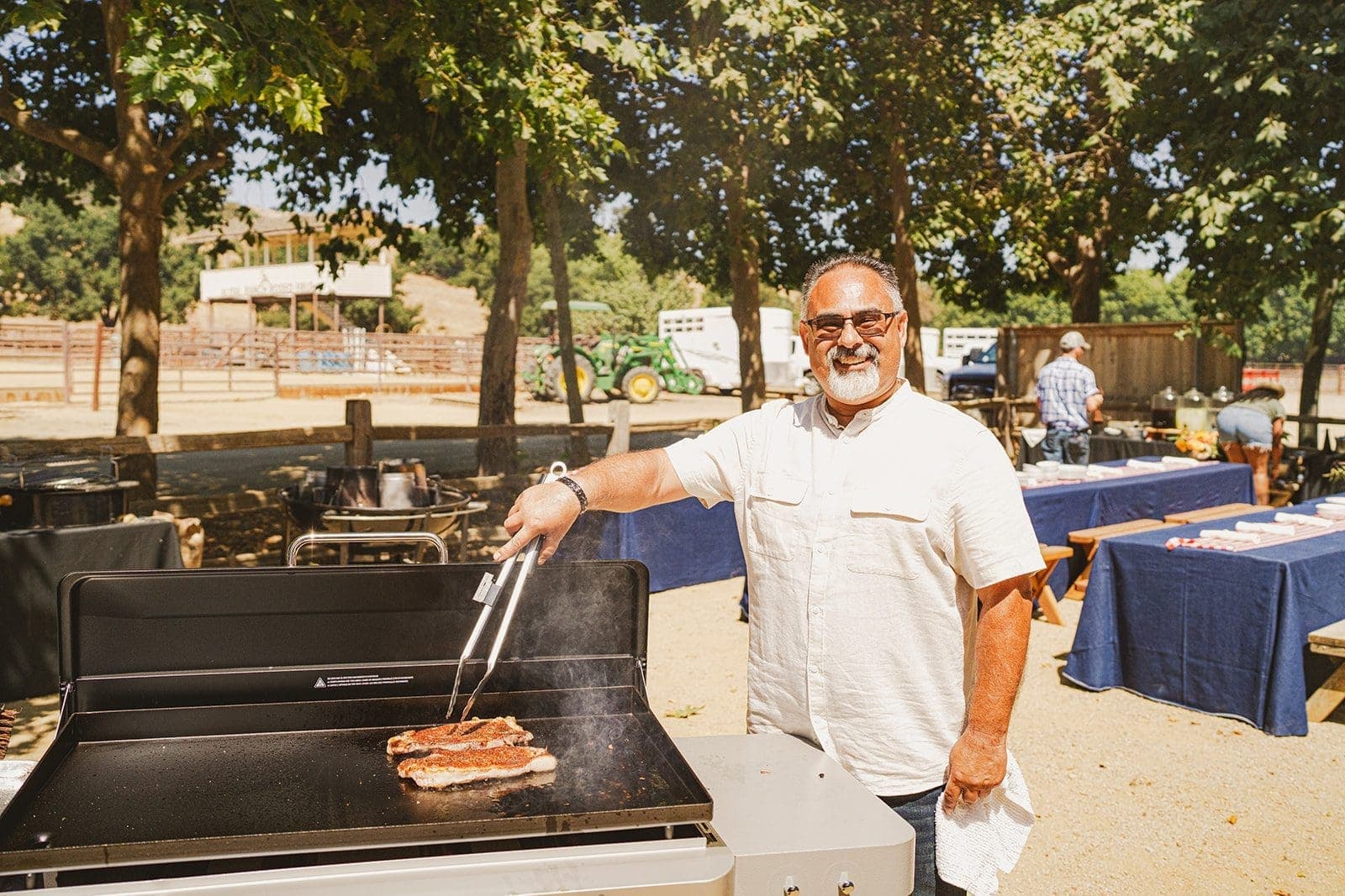 man holding tongs over a bbq