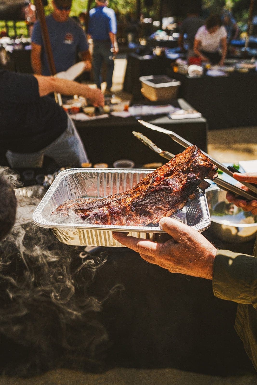 person holding ribs in an aluminum pan