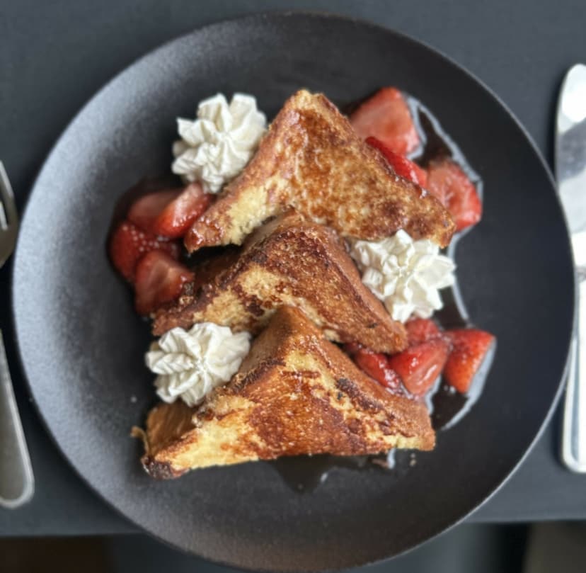 french toast with strawberries and whipped cream on a plate