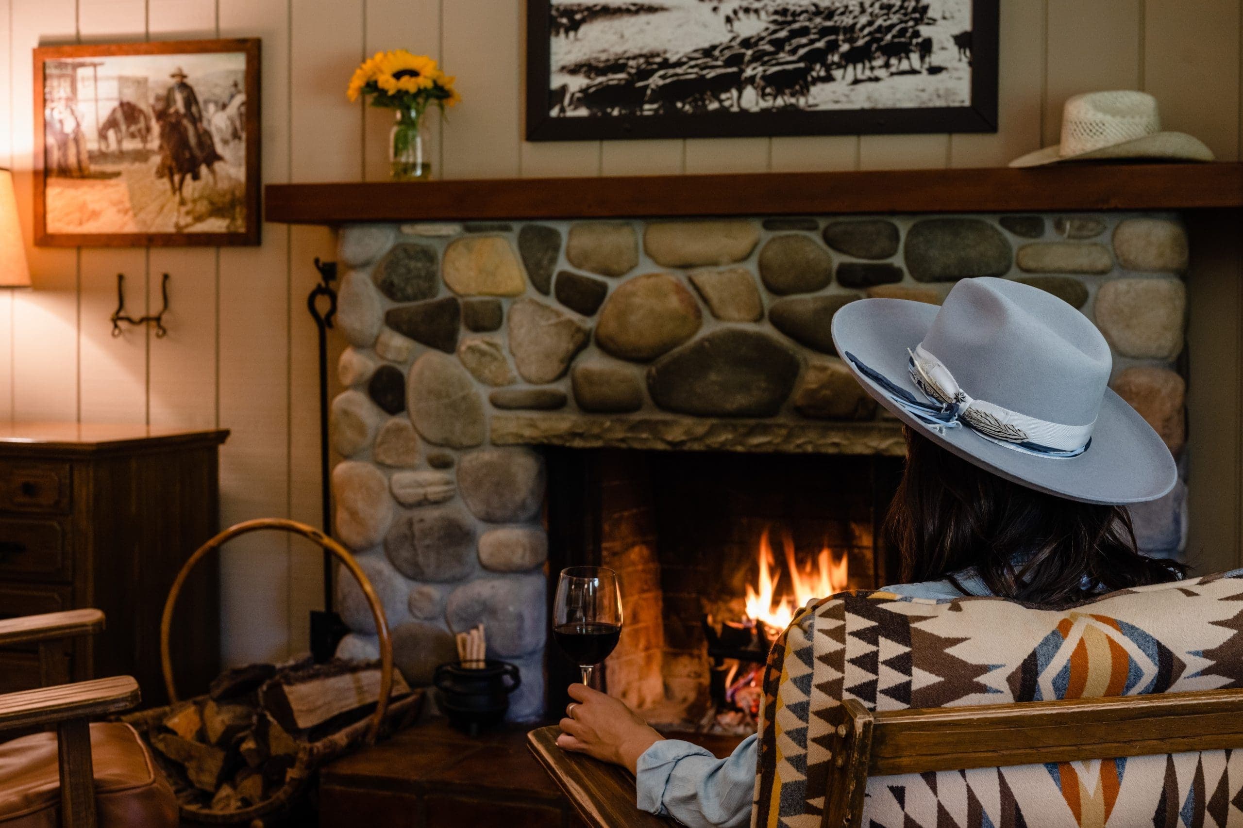 person sitting on chair by fireplace drinking wine in a glass