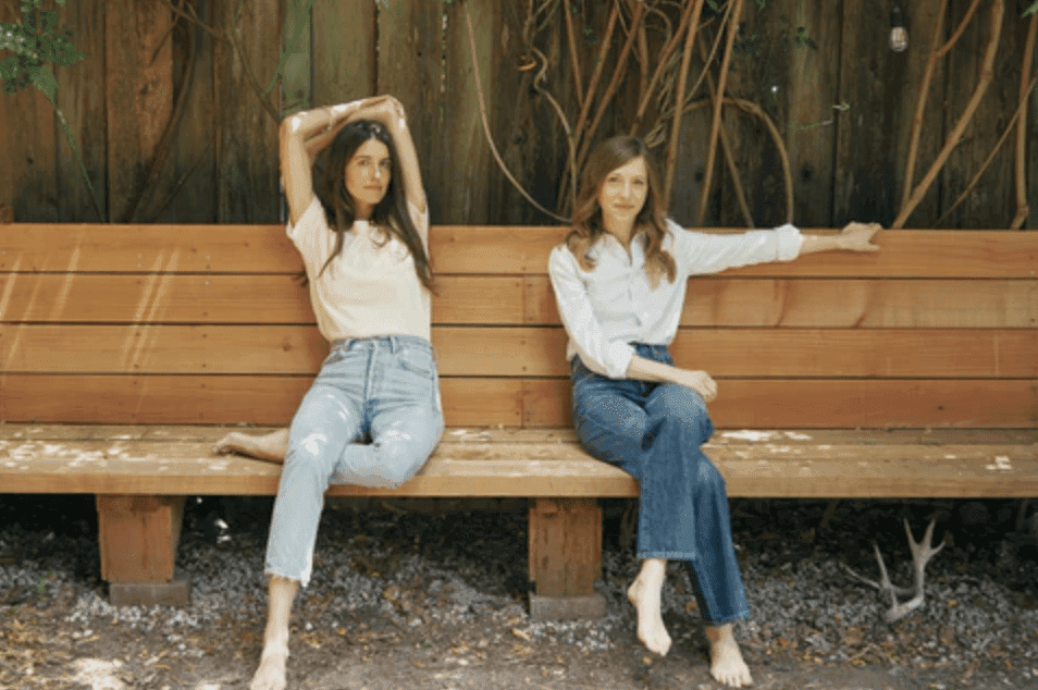 two people sitting on a bench posing