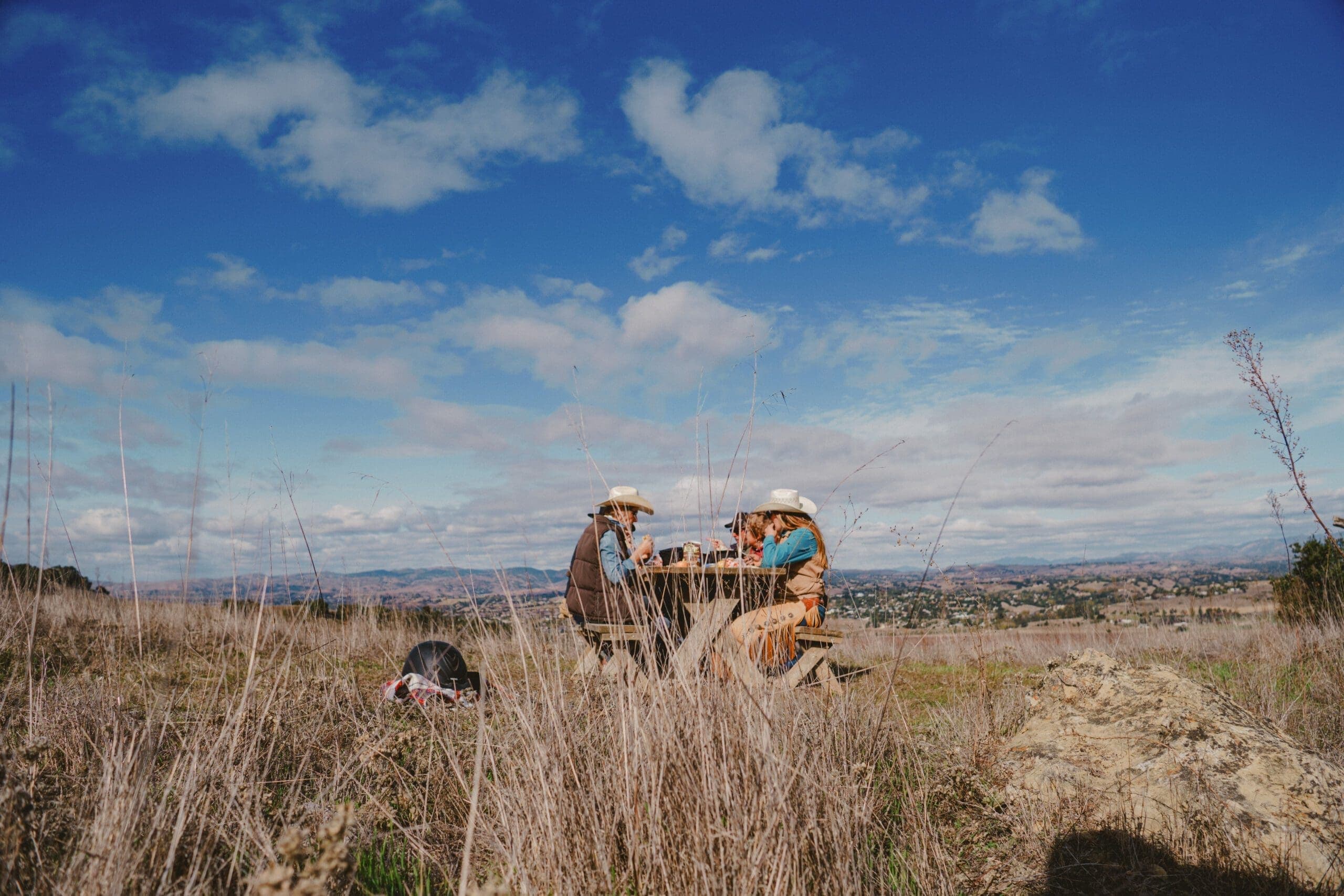 group of people eating on a picnic bench outside