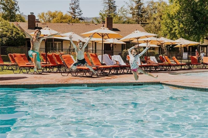 three kids jumping in a pool
