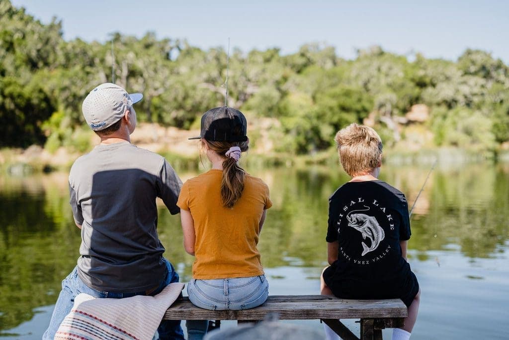 three kids sitting on bench fishing
