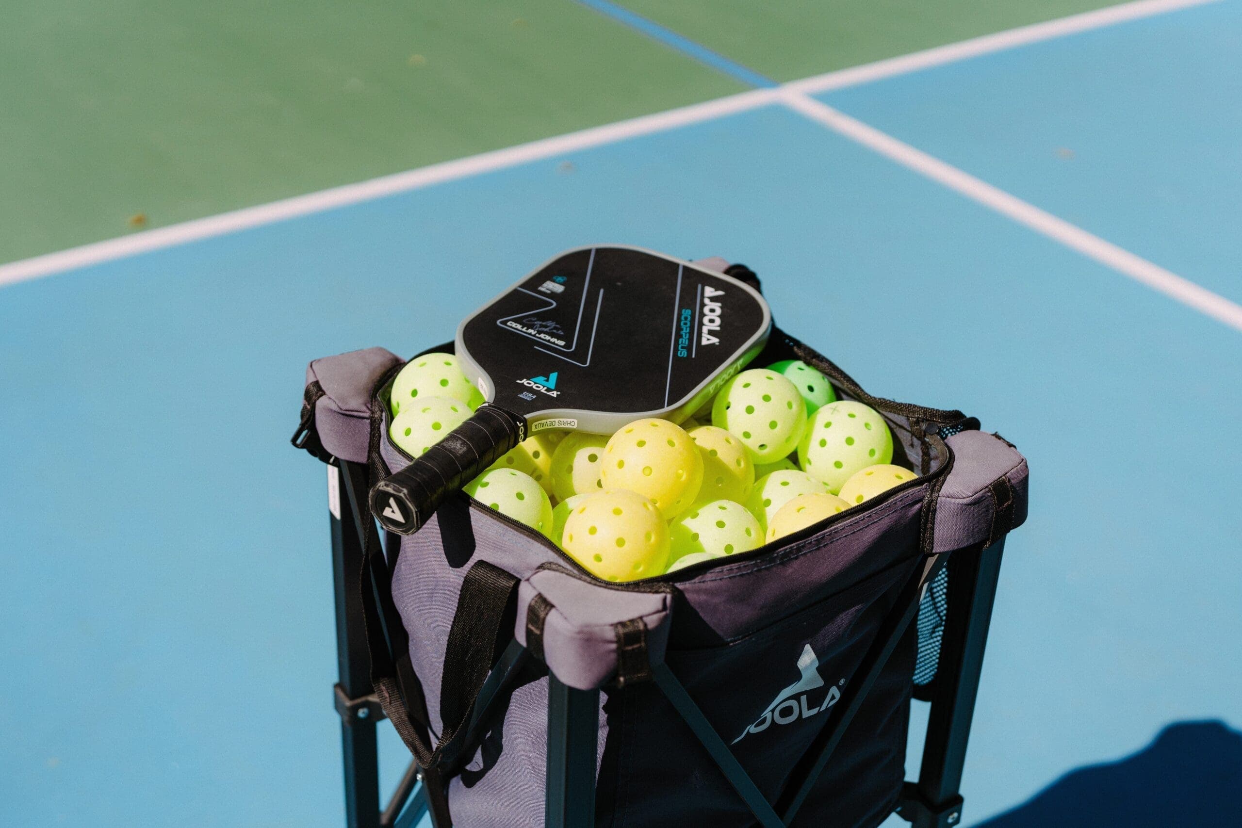 pickleball racket on top of a basket full of pickleballs