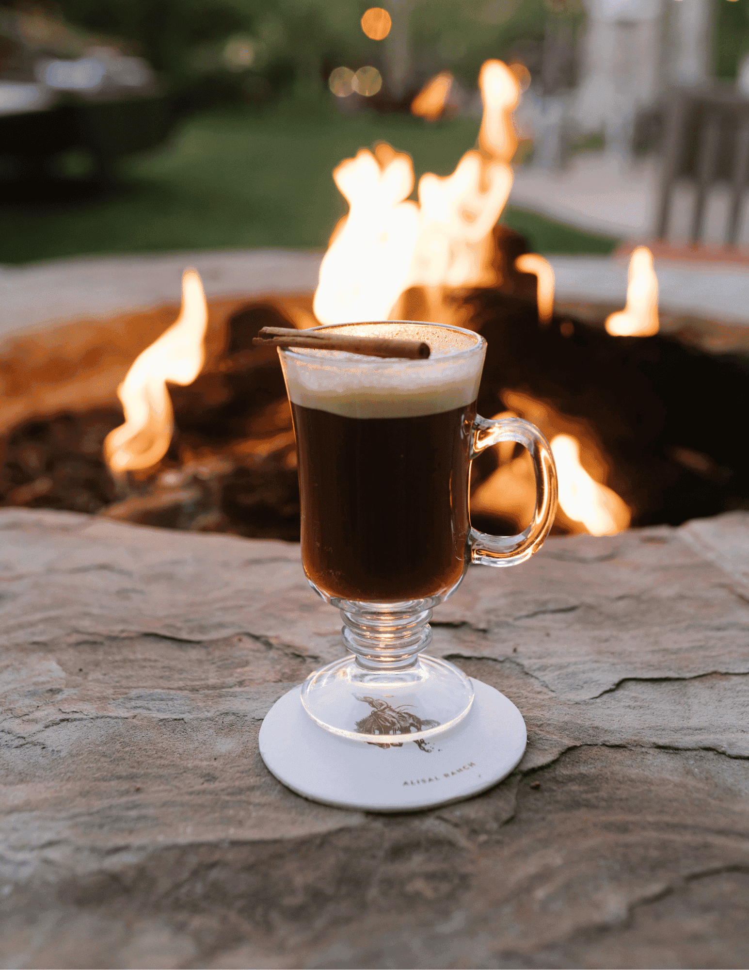 drink in a glass by a fire pit