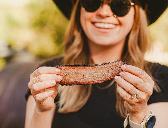 person holding slice of barbecued meat