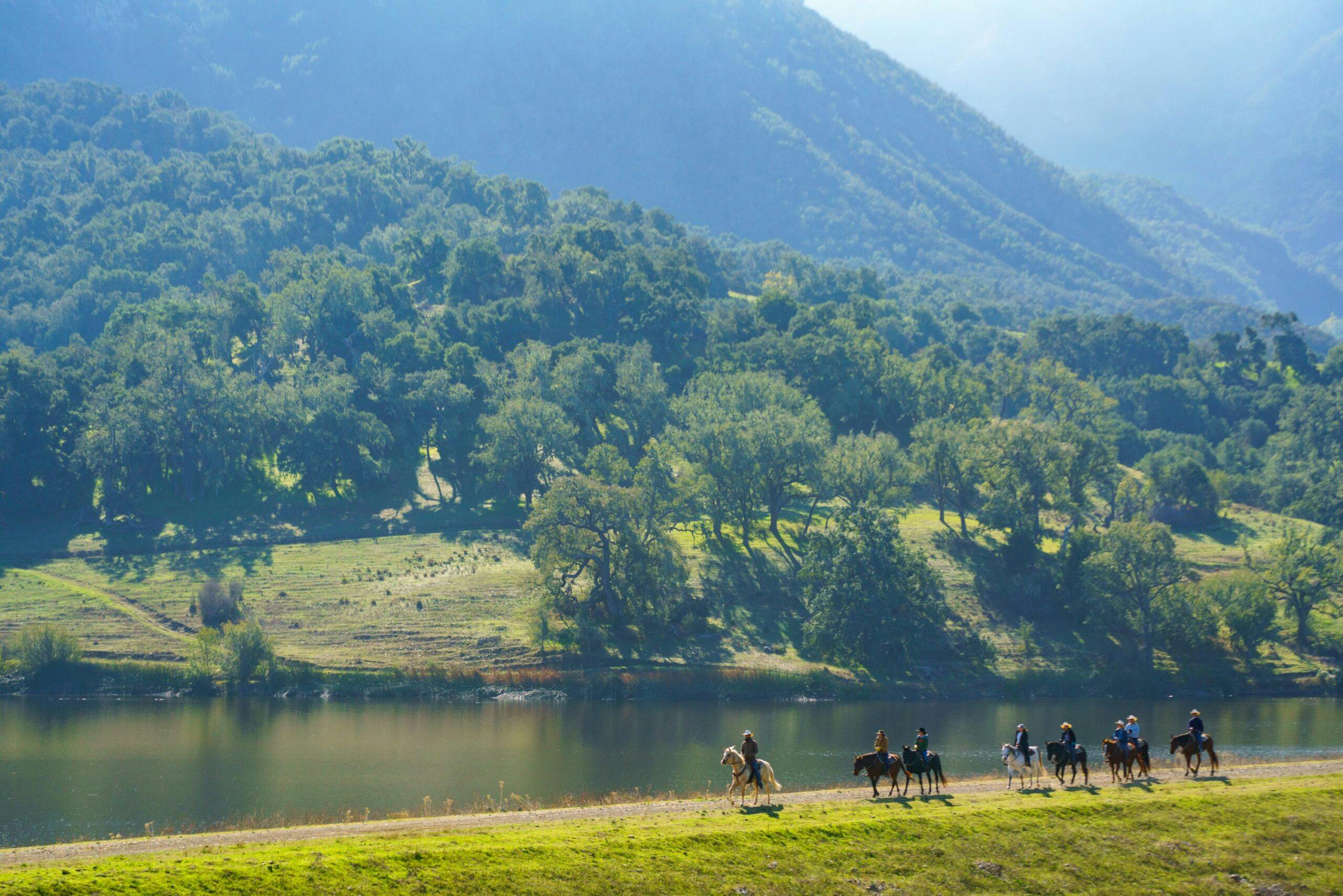people riding horses along Alisal Lake