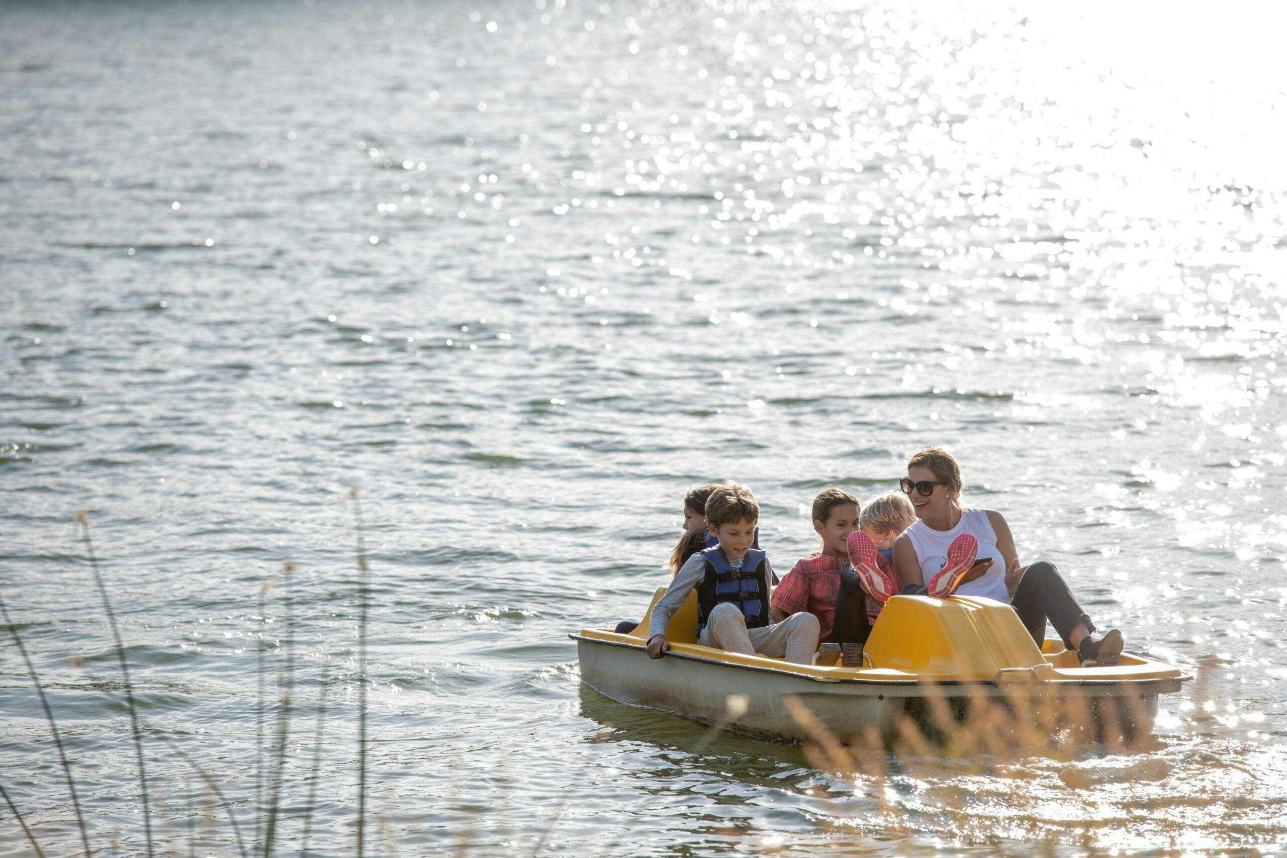 adult and kids using a pedal boat on the lake