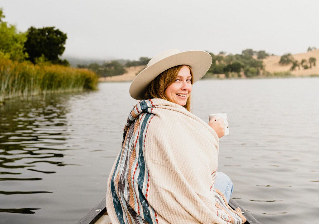 person cozy under a blanket on a canoe