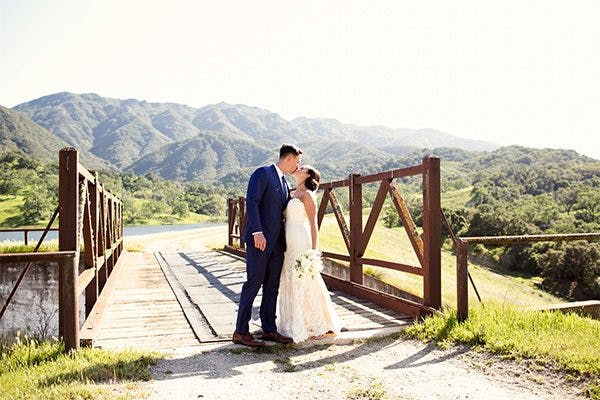 Bride and groom kissing on a bridge at the Alisal Guest Ranch & Resort