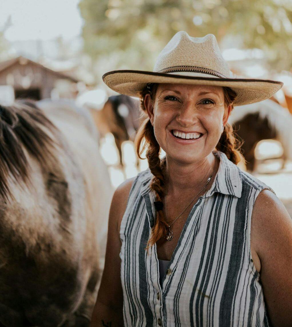 person in a cowboy hat standing beside a horse