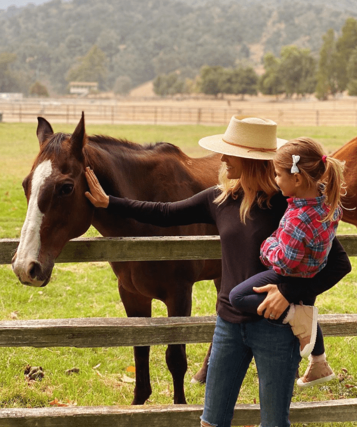 person holding child while petting a horse