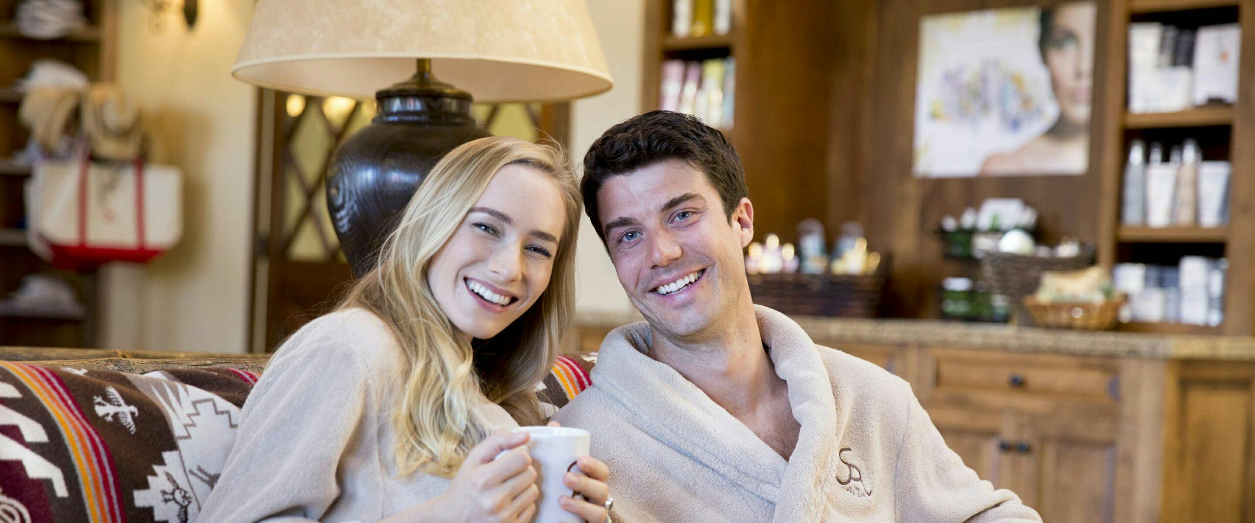 couple relaxed on a couch smiling for a photo