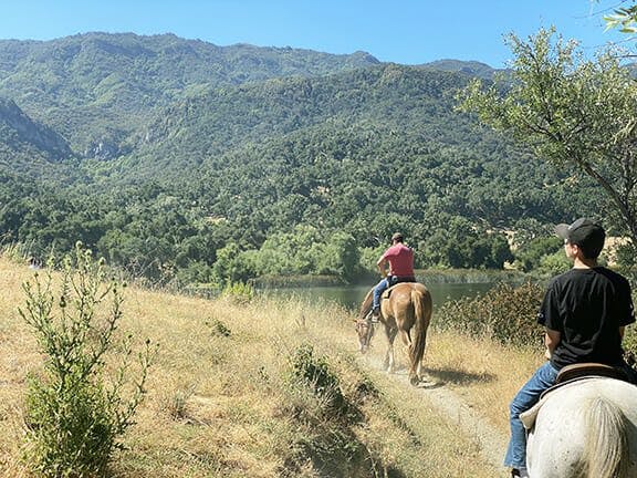 two people horseback riding by Alisal lake